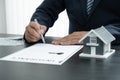 The hand of the real estate agent, holding a pen and drafting an agreement on the home insurance contract documents, along with Royalty Free Stock Photo