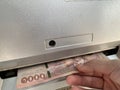 The hand is receiving money from the automatic withdrawal machine, ATM