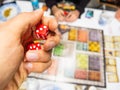 Hand with red dice on the game board with a three