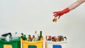 Hand in red glove throwing paper into one of three colorful green, yellow and white recycle garbage bins full of rubbish Royalty Free Stock Photo