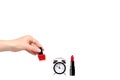 Hand with red nail polish, lipstock and alarm clock