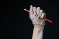 Hand with red pencil tied with rope