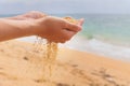 The hand releases the falling sand. Golden sand flows through your fingers on a sea background. Summer beach holiday and Royalty Free Stock Photo