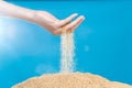 Hand releasing dropping sand. Fine Sand flowing pouring through fingers against blue background. Summer beach holiday vacation and Royalty Free Stock Photo