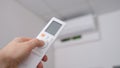 Hand with remote control is directed to air conditioner on wall Royalty Free Stock Photo