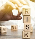 Hand removes blocks with the word Risk. The concept of reducing possible risks. Insurance, stability support. Financial pillow.