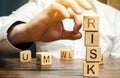 Hand removes blocks with the word Risk. The concept of reducing possible risks. Insurance, stability support. Financial pillow.