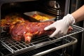 hand removing bbq ribs from oven with oven mitt