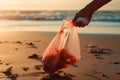 Hand Removing Plastic Bag from Sandy Beach