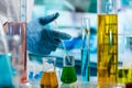 Hand of researcher with pipette measuring sample in beaker of liquids in the chemical lab