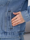 A hand resting casually in a pocket of a blue denim jacket, with visible stitching and a button detail on the sleeve, showcasing Royalty Free Stock Photo