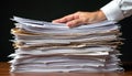 Hand rests on large stack disorganized papers documents on wooden table. Represents overwork, burnout, business overload, Royalty Free Stock Photo