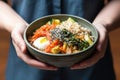 hand revealing sesame-seed crusted bibimbap in bowl