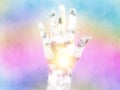 Hand reveals the rising sun shining through the clouds at the Litha midsummer festival.  Rain and rainbow colours in the backgroun Royalty Free Stock Photo