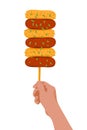 Hand with rice cake skewers on stick. Korean street food Sotteok Sotteok. Fried sausages rice cakes on stick in turns