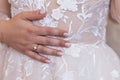 The bride holds her hand on a white beautiful bridal dress and shows her engagement ring. Royalty Free Stock Photo