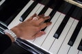 hand with a ring striking white piano keys