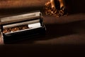 Hand-rolled cigarette, rolling machine, cigarillos, scattered tobacco on background, cigarette roll with filter, cigarette filters