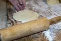 A hand rolls out dough on a wooden surface, showcasing culinary preparation in a rustic kitchen. Flour dust adds texture Royalty Free Stock Photo