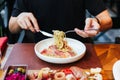 Hand rotate the shaft of the fork, twining the strands of pasta around the tines for eating Fettuccine Carbonara with parma ham. Royalty Free Stock Photo