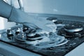 A hand In a rubber glove cleans a gas stove. Kitchen cleaning. Blue color toned Royalty Free Stock Photo