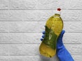 Hand in rubber glove holds bottle of detergent. Place for text