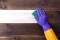 A hand in a rubber glove washes a wooden surface. Cleaning, room cleaning