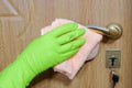 A hand in a rubber glove wipes dust with a rag from a door handle. Cleaning service Royalty Free Stock Photo