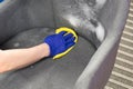 Hand in rubber gloves collects cleaning agent from the upholstery of the chair