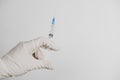 hand in rubber gloves with a syringe with a liquid substance on a white background, place for text