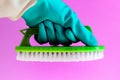 Hand in rubber latex glove with Handheld floor brush cleaning in on pink background