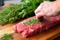 hand rubbing herbs onto steak to check stickiness