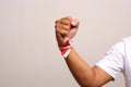 Hand's man holding indonesian flag with red whit ribbon on the wrist. Isolated on gray background Royalty Free Stock Photo