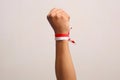 Hand's man holding indonesian flag with red whit ribbon on the wrist. Isolated on gray background Royalty Free Stock Photo