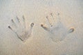 Hand`s prints on the sand of the beach with sea wave. Two people`s hands marks on the sand