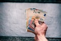 HandÃÂ´s of young man holding a money. Banknotes on a stone background. Euro money bank notes of different value. Royalty Free Stock Photo