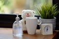 Hand sanitizer,white cup,teddy bear and alarm clock on wood table with green nature background while Covid-19  home quarantine Royalty Free Stock Photo