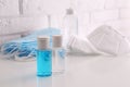 Hand sanitizers and respiratory masks on table near white brick wall.