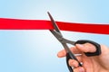 Hand with scissors cutting red ribbon - opening ceremony Royalty Free Stock Photo