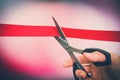 Hand with scissors cutting red ribbon - opening ceremony Royalty Free Stock Photo