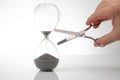 hand with scissors near the hourglass. time stop concept
