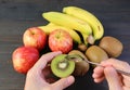 Hand Scooping a Cut Kiwifruit with Assorted Fresh Fruits in the Backdrop Royalty Free Stock Photo