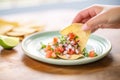 hand scooping pico de gallo with a tortilla chip