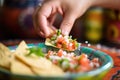 hand scooping pico de gallo with a tortilla chip