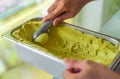 hand scooping a scoop of Avocado ice cream into a spoon in fridge