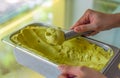 hand scooping a scoop of Avocado ice cream into a spoon in fridge