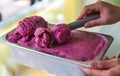 hand scooping a scoop of Mulberry ice cream into a spoon in fridge