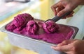 hand scooping a scoop of Mulberry ice cream into a spoon in fridge