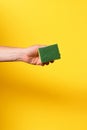 hand with a scourer on yellow background Royalty Free Stock Photo