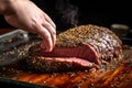 hand seasoning beef roast with cracked pepper